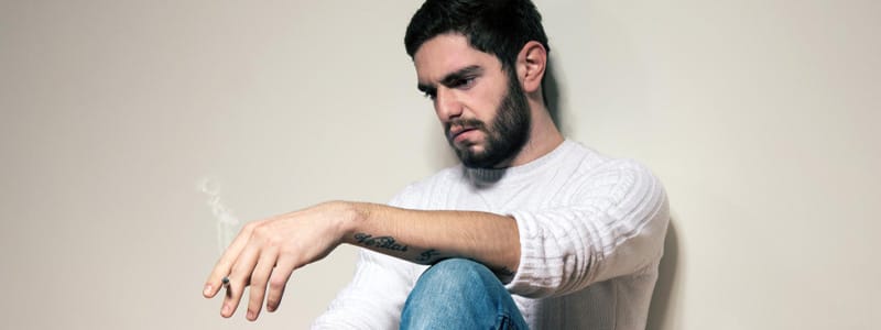 Person delaying quitting smoking, feeling stuck between decisions